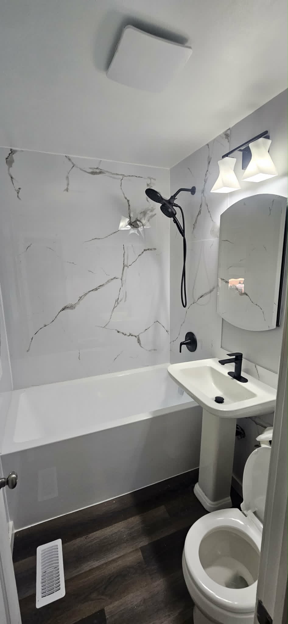 Renovated bathroom with marble-look tub surround and black fixtures